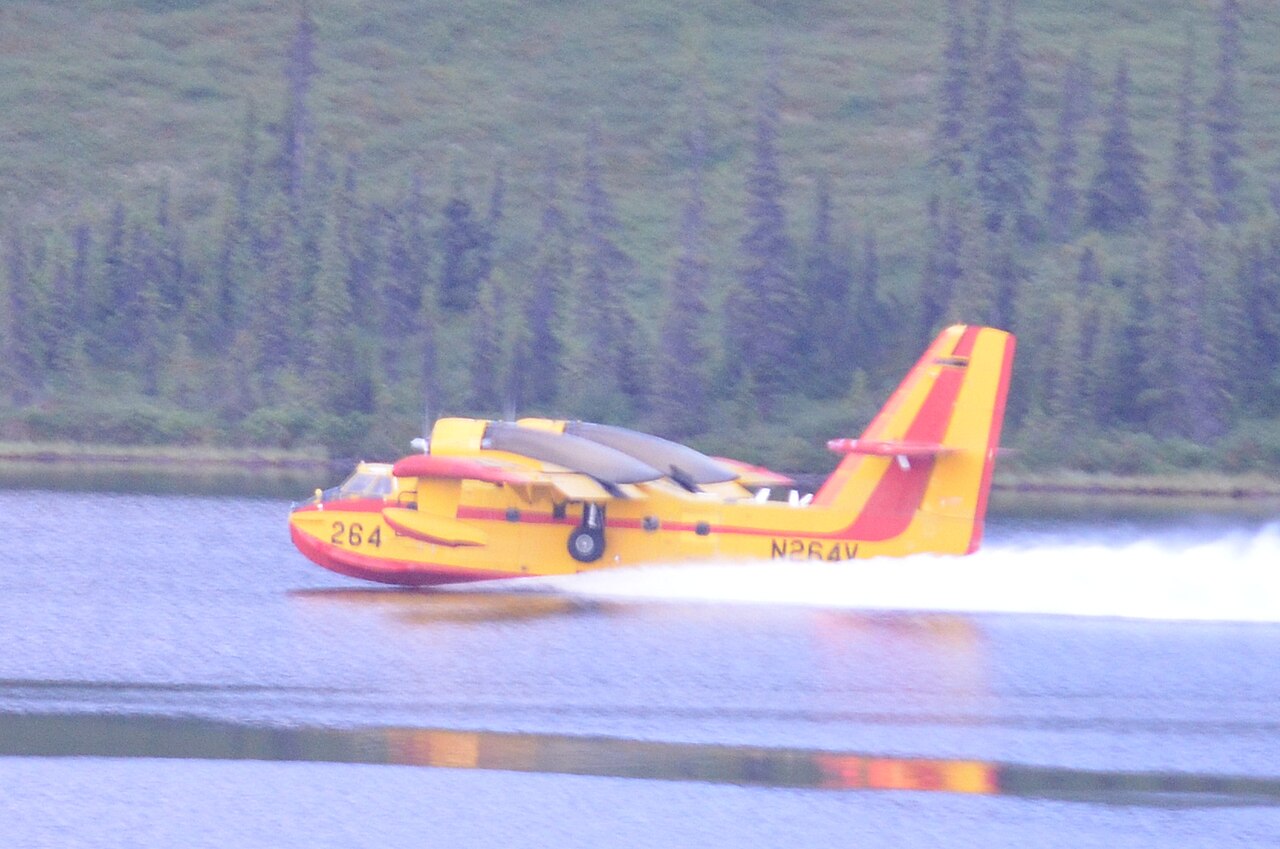 Un bombardier d'eau amphibie écope à la surface d'un plan d'eau