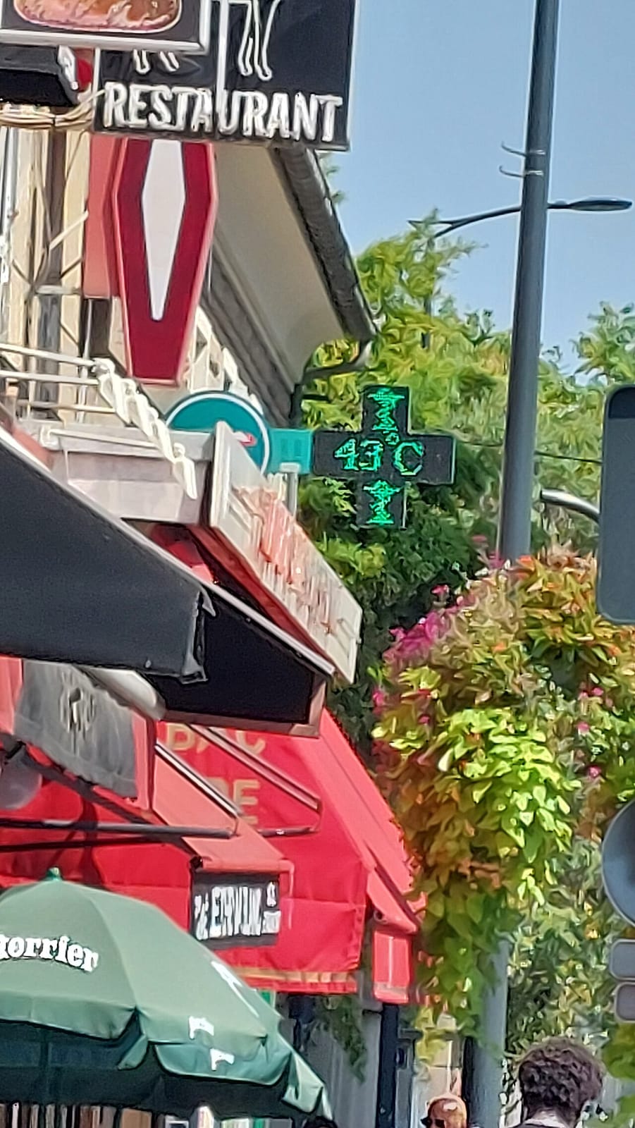 Une croix de pharmacie verte affiche 43 °C dans une rue commerçante de Colombes, en région parisienne, pendant l'été 2026