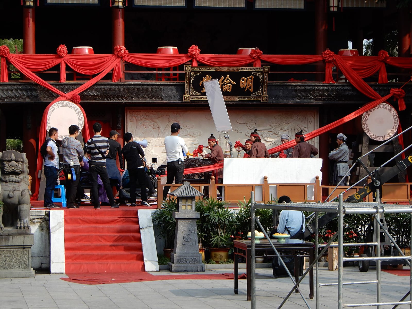 Tournage d'une série en costumes sur un décor extérieur des studios de Hengdian, avec figurants et techniciens
