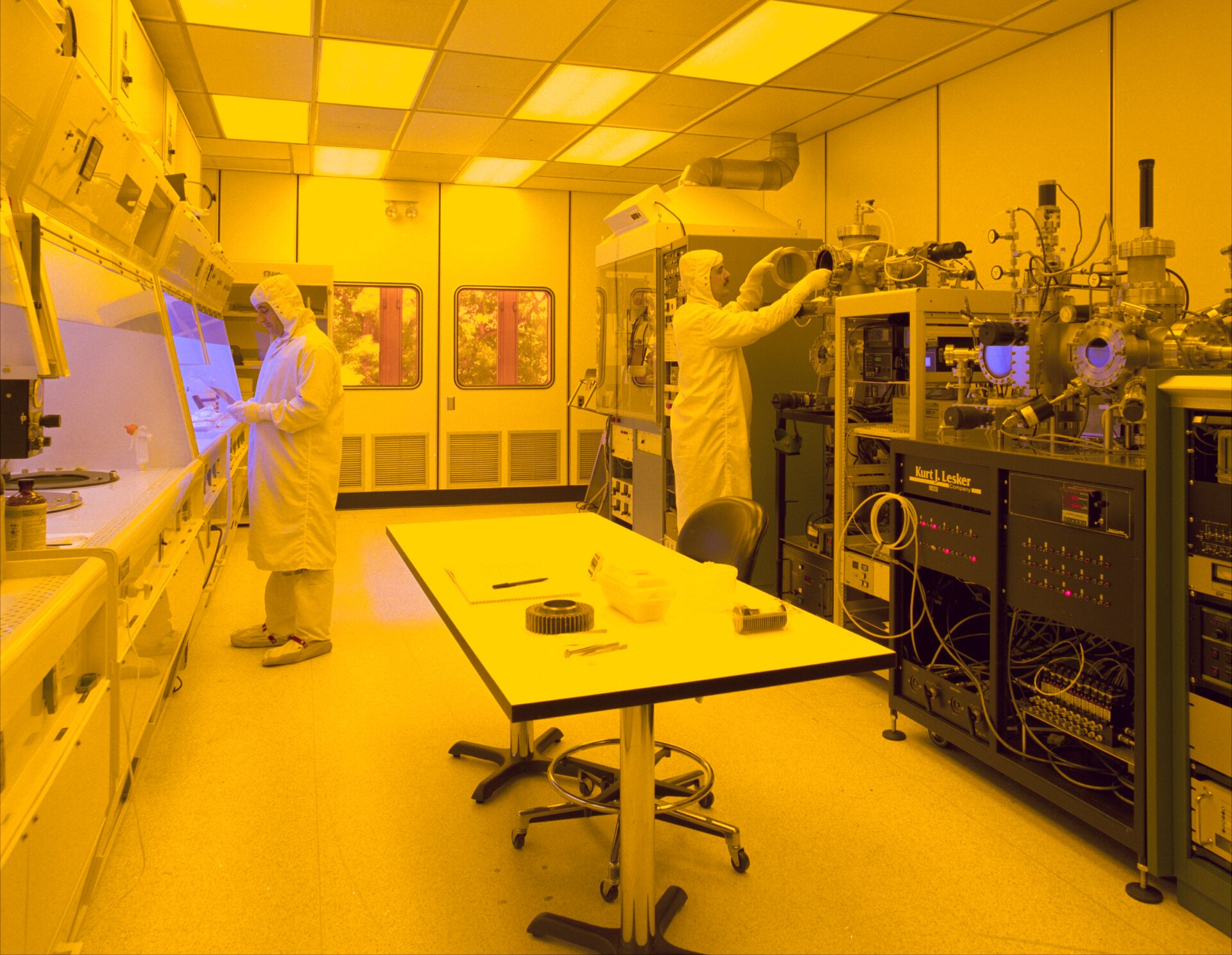 Technicien en combinaison intégrale dans une salle blanche de microfabrication, entouré d'équipements